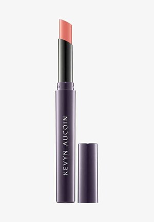 Lipstick in sleek purple tube with black accent. Removable cap. Product has a soft coral color and a curved, slanted tip for application.