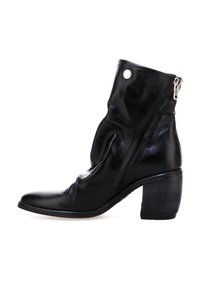 Botín de cuero negro hasta el tobillo con puntera redondeada, parte superior caída, cremallera lateral y tacón apilado. Textura suave con acentos mínimos.