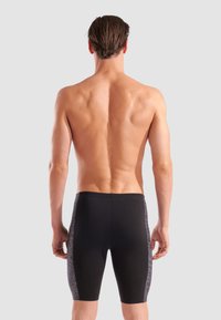 Schwarze Badshorts mit passgenauer Form, die über strukturierte graue Seitenpanels verfügen. Hergestellt aus dehnbarem Material, geeignet für aquatische Aktivitäten.