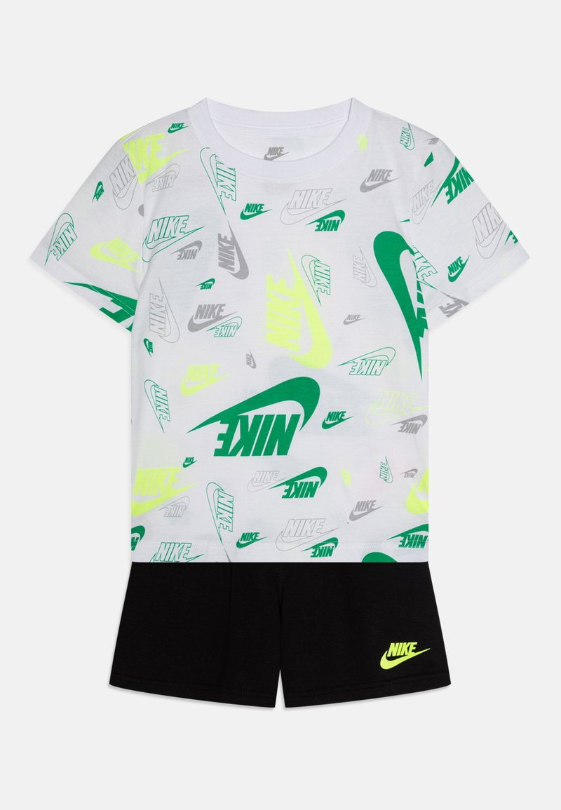 Fehér póló, különböző zöld és szürke Nike logókkal, fekete rövidnadrággal, amelyen egy kis sárga Nike logó van. Köznapi stílus, rövid ujjú.