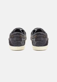 Scarpe da ginnastica grigio scuro in tela con suole in gomma bianca, dotate di lacci tondi e cuciture decorative laterali. Design classico delle sneaker, forma a profilo basso.