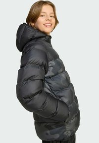 Doudoune noire avec capuche, présentant une finition texturée, un design à carreaux horizontal et de subtils accents de camouflage gris.