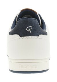 Basket blanc avec un talon bleu marine, en cuir lisse, avec un accent tan sur le col et un logo "Redskins" en relief sur le talon.