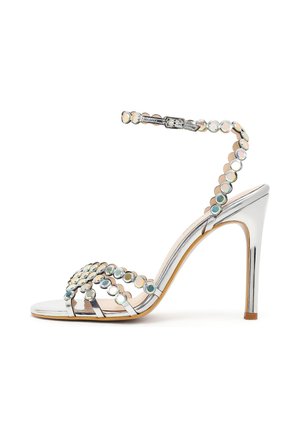 Sandale à talons argentés avec bride à la cheville et clous ronds irisés décoratifs sur les brides et le talon, design à bout ouvert.