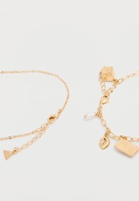 Deux bracelets en chaîne dorée avec fermoirs mousqueton, l'un avec un pendentif triangle, l'autre avec un dé, des lèvres, un pendentif rectangulaire et un petit pendentif en perle.