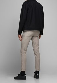 Svart jacka, ljusrandiga byxor, svarta sneakers. Enkel design med en strukturerad passform, slät textur och standardkrage.