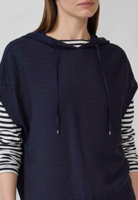 Marinefarbener Kapuzenpullover mit strukturiertem Finish, ausgestattet mit Kordeln und kontrastierenden gestreiften Ärmeln in Weiß und Marine.