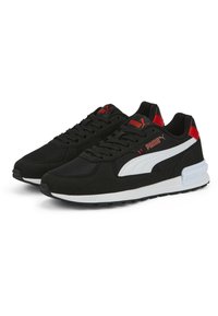Chaussures de sport noires avec un dessus en synthétique, des accents blancs, un branding rouge et un design en maille texturée. Semelle en caoutchouc avec adhérence.
