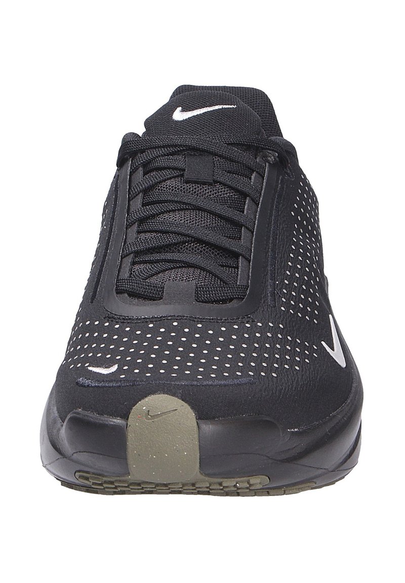 Zapatilla deportiva negra con parte superior de malla que presenta perforaciones blancas y un logo de Nike blanco. Suela gruesa con un acabado texturizado en negro y gris.