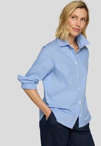 Light blue striped shirt with white and dark blue lines. Features a large collar and rolled-up sleeves. Button-front design, made of crisp fabric.