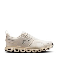 Baskets de course beiges avec un dessus en mailles texturées, un design à lacets et une semelle intermédiaire rembourrée avec une semelle extérieure segmentée pour plus de flexibilité.