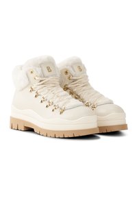 Białe skórzane buty trekkingowe z miękkim futrzanym kołnierzem, złotymi oczkami i sznurowadłami. Grube, fakturowane gumowe podeszwy w beżowym kolorze z falistym wzorem.