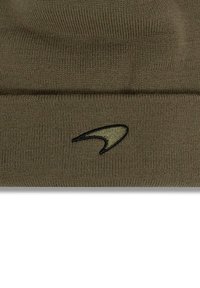 Oliwkowa dzianinowa czapka z mankietem i czarnym logo. Wykonana z miękkiego, teksturowanego materiału, zaprojektowana dla ciepła i komfortu.
