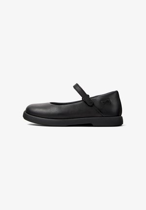 Black Mary Jane shoe featuring a flat sole, rounded toe, and a decorative strap across the instep. Smooth leather upper and subtle logo detail.