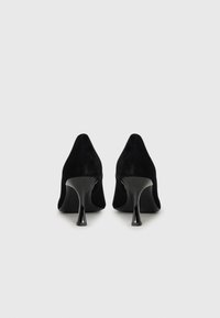Black suede high-heeled shoes with a pointed toe and sleek design. The heel is curved with a glossy finish, emphasizing a modern silhouette.