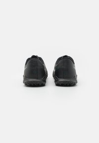 Zapatillas deportivas negras con una parte superior sintética texturizada, tacón redondeado y suela de goma duradera con pequeños tacos de tracción.