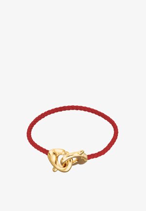Bracelet en cuir tressé rouge avec une fermeture en métal doré ornée d'un motif de nœud et un petit pendentif attaché. Texture lisse et matériau durable.