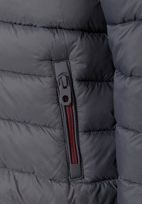 Dark gray padded jacket section featuring a zippered pocket with red and black accents and horizontal quilted texture.