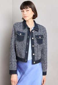 Granatowa marynarka z tweedu z akcentami z denimu. Posiada zapięcie na guziki, kieszenie z przodu oraz skrócony krój. Miękka tekstura z kontrastującymi kolorami.