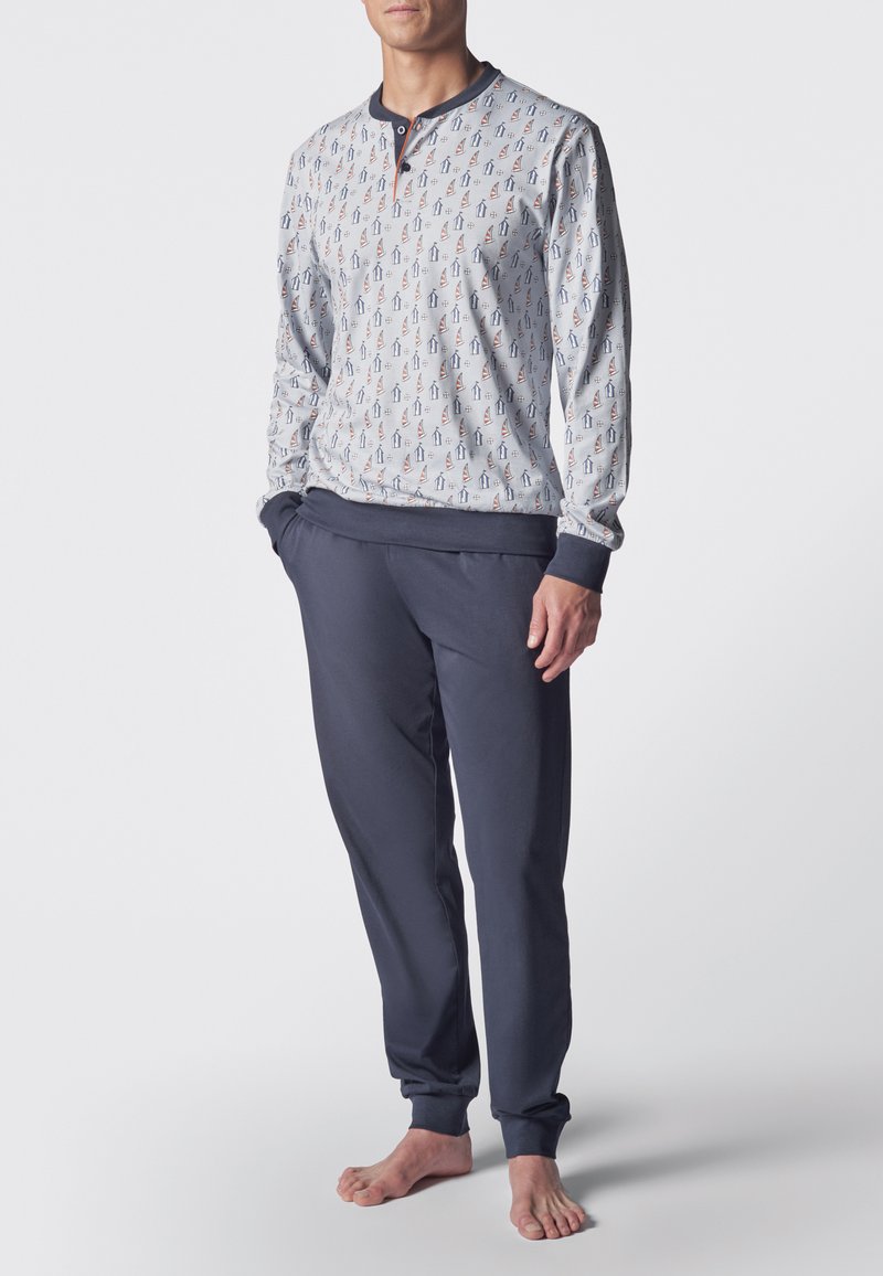 Pigiama a maniche lunghe di colore grigio chiaro con un motivo di piccole barche a vela, abbinato a pantaloni blu navy con cintura elastica. Tessuto morbido in misto cotone.