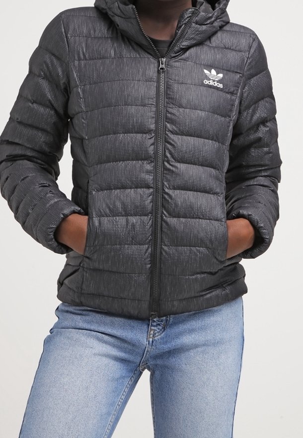 Svart kviltad puffjacka med huva, dragkedjestängning och två sidofickor. Har en subtil strukturerad design och Adidas-logotyp på bröstet.