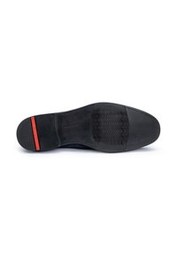 Semelle de chaussure noire avec une surface lisse et texturée, présentant une bande d'accent rouge au niveau du talon et un logo embossé sur le caoutchouc.