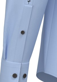 Tessuto di camicia a righe blu chiaro con un taglio elegante. Presenta una chiusura con bottoni e un piccolo logo nero sulla manica. Tessuto misto poliestere.
