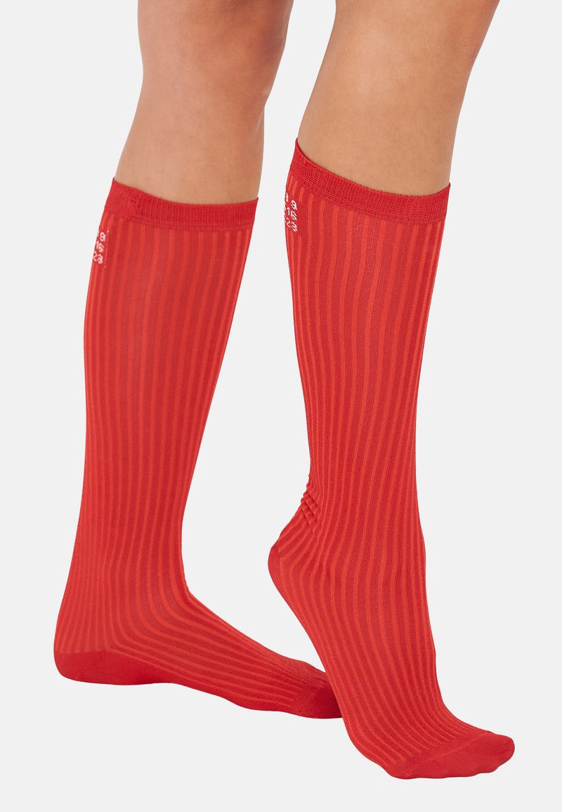 Red knee-high socks with vertical ribbed texture and a solid color throughout. Stretchy material with a reinforced cuff at the top.