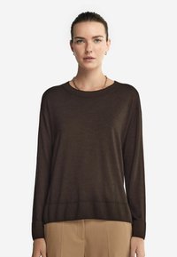 Brauner Pullover mit langen Ärmeln, geripptem Halsausschnitt und Saum, aus einem weichen Material gefertigt. Verfügt über eingesetzte Schultern und eine lockere Passform.