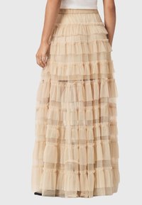 Μακριά, πολυεπίπεδη φούστα από λευκή τούλινη ύλη. Διαθέτει στρώσεις από ρουφ, και ελαστική μέση για μια ρέουσα, υφή.