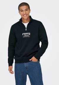 Zwarte quarter-zip sweatshirt gemaakt van een katoenmix. Bevat het witte "4TH QUARTER Athletics" logo op de borst en ribgebreide manchetten. Gepaard met blauwe spijkerbroek.