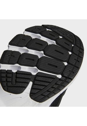 Semelle en caoutchouc texturée noire et blanche d'une chaussure de course avec des rainures profondes et un profil segmenté pour l'adhérence et la flexibilité.