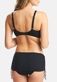 Musta uimapukusarja, joka sisältää tekstuurilla varustetun kietaisuhameen, jossa on nyörit, sekä yhteensopivan rintaliivin, jossa on säädettävät olkaimet ja koukkuulgus.