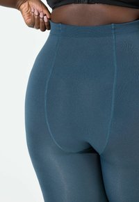 Türkise, hochgeschnittene Leggings mit einer gerippten Textur, die ein nahtloses Design und verstärkte Nähte an den Seiten und am Bund aufweisen.