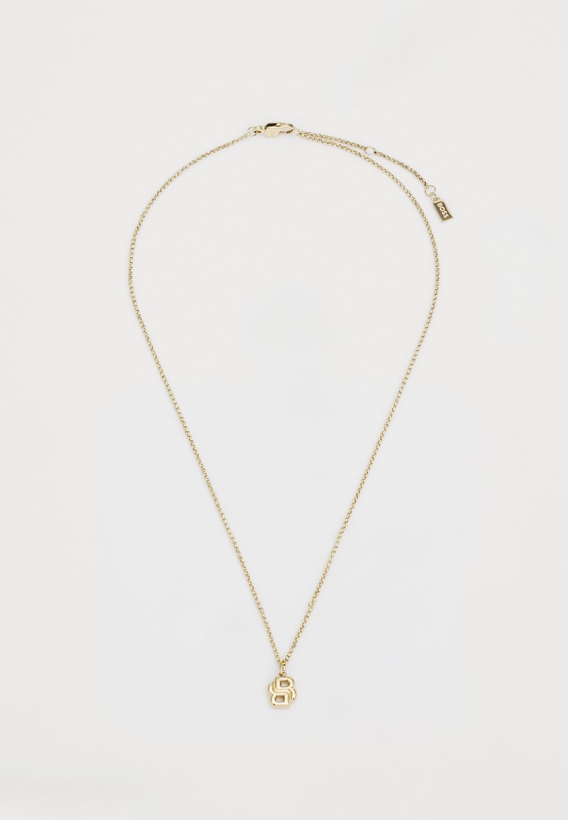 Χρυσό μεταλλικό κολιέ με λεπτή αλυσίδα και κεντρικό pendant σε σχήμα γράμματος 'B'. Διαθέτει κούμπωμα και αλυσίδα επέκτασης για ρύθμιση.