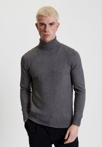 Maglione grigio a collo alto realizzato in un morbido materiale a maglia, con maniche lunghe e un design aderente. L'orlo e i polsini sono a coste.