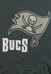Un tessuto grigio scuro presenta una bandiera pirata stilizzata con un teschio e spade incrociate, affiancata dal testo "BUCS" in lettere bianche in grassetto.