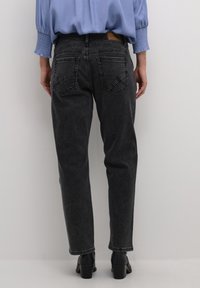 Mustad denim püksid sirge läbilaske ja tikanditega tagataskutega. Kanda helesinise särgi ja mustade kontsakingadega.