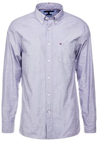 Vaaleansininen nappipaita kudotusta kankaasta, jossa on rintatasku, pitkät hihat ja klassinen kaulus kontrastiväreillä.