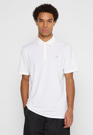 Polo bianca con maniche corte e design con colletto. Presenta un logo Adidas grigio tenue sul petto sinistro e una texture del tessuto liscia.
