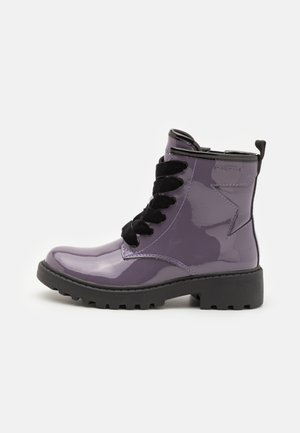 Botte de cheville en cuir verni violet avec des lacets noirs, semelle épaisse et coutures contrastées. Présente un détail de logo sur le côté.
