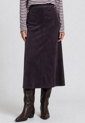 Person wearing a black suede midi skirt, brown leather knee-high boots, and a long-sleeve striped shirt, standing with hands relaxed.