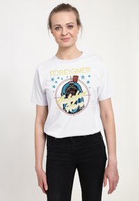 Vit bomull t-shirt med ett grafiskt tryck som visar en jukebox, stjärnor och texten "Foreigner Jukebox Hero" i flerfärgade bokstäver.