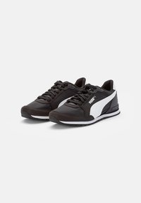 Scarpe da atletica nere con finitura opaca, dotate di una striscia bianca, punta tondeggiante, lacci piatti e suola in gomma. Logo visibile di lato.