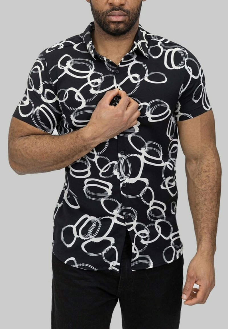 Chemise noire à manches courtes avec un motif circulaire blanc, fermeture à boutons sur le devant et texture de tissu lisse.