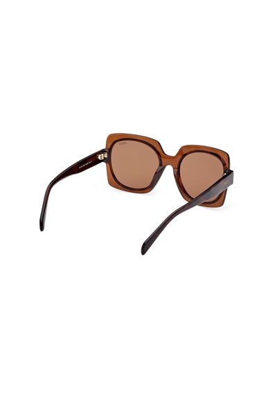 Gafas de sol marrones de gran tamaño con un marco hexagonal y lentes degradados. Material plástico con patillas oscuras en contraste y detalles dorados.