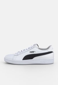 Baskets blanches Puma avec logo en forme de bande noire, lacets blancs et semelle rembourrée, vues de côté externe sur un fond uni.