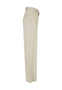 Pantalon beige à jambes droites avec poches latérales et passants pour ceinture, montré de profil sur fond blanc.