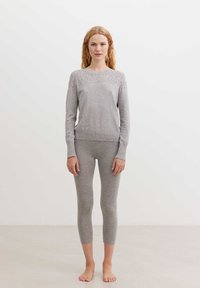 Hallikas kudumine pika varrukaga topp, millel on mustriga õlg ja sobivad lühikesed legginsid. Pehme tekstuur, modelleeritud disain, minimalistlik stiil.