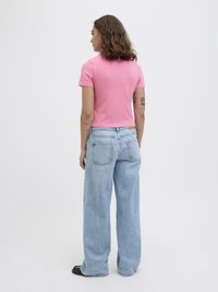 Rosa t-skjorte med korte ermer og en tettsittende design, kombinert med lyseblå vide jeans med en lett falmning og to baklommer.